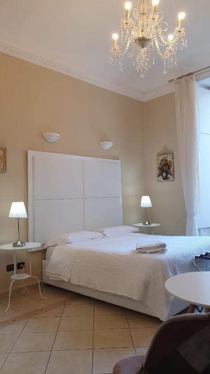 a bedroom with a bed and two tables and a chandelier at B&B Diana in Syracuse