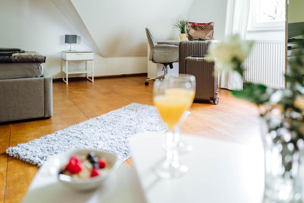 a glass of orange juice on a table in a living room at Doppelzimmer 150 m zur TA (Nr. 6) in Hameln