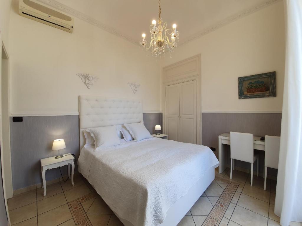 a bedroom with a bed and two tables and a chandelier at B&B Diana in Siracusa