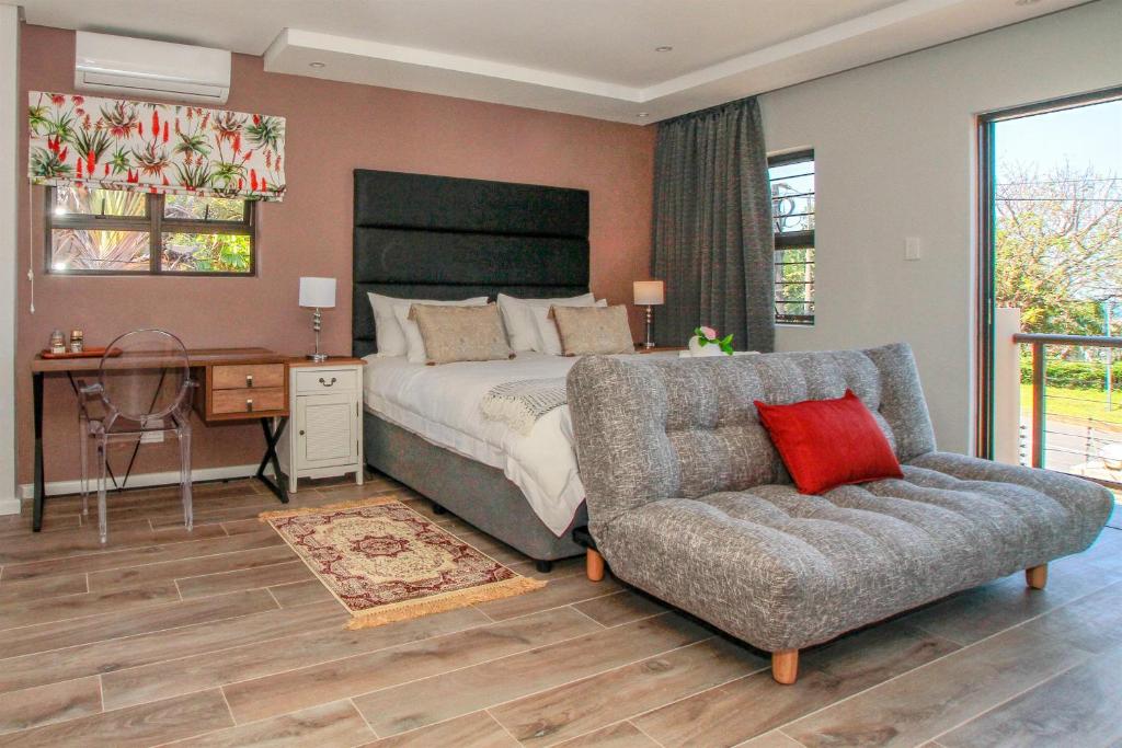 a bedroom with a bed and a couch and a chair at Casa Ridge Self-catering in Durban