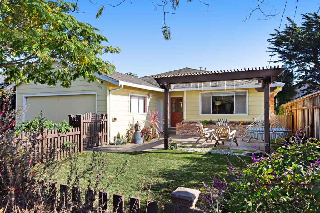 a yellow house with a fence and a yard at Westside Beauty in Santa Cruz