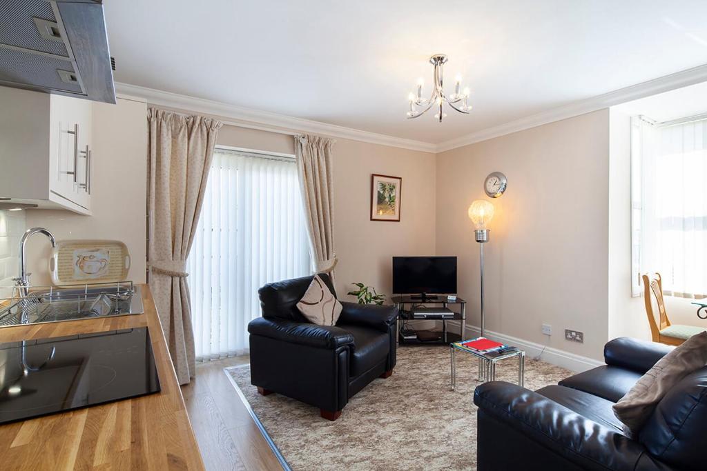 sala de estar con sofá de cuero negro y TV en Burbage Holiday Lodge Apartment 4, en Blackpool