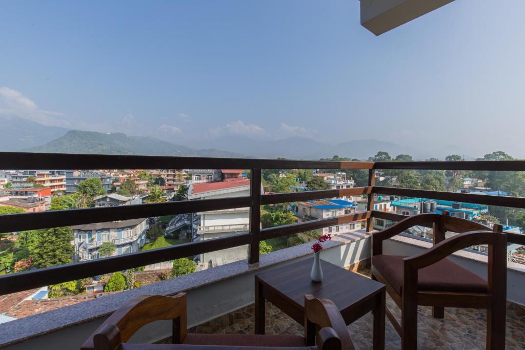 balcón con mesa, sillas y vistas en Hotel Snow Peak, en Pokhara