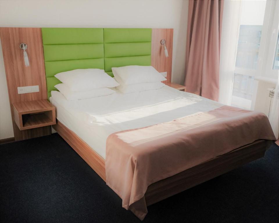 a bedroom with a large bed with a green headboard at BOUTIQUE HOTEL 1967 AQSAI in Aksay
