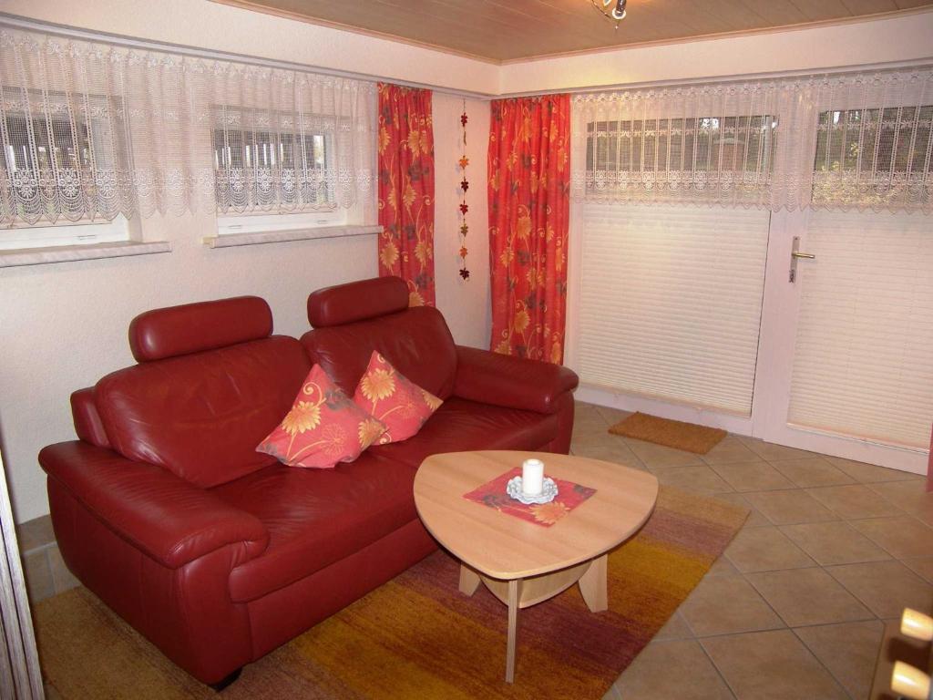 a living room with a red leather couch and a table at Ferienwohnung Krentz in Neu Sallenthin