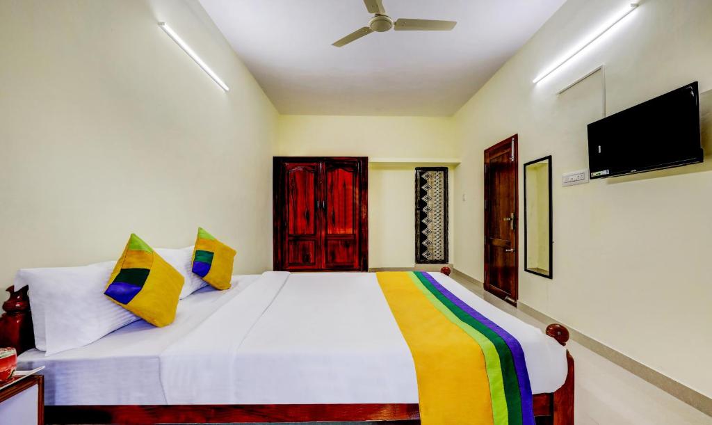 a bedroom with a white bed with a tv on the wall at Hotel Umaiyyal International in Kanyakumari