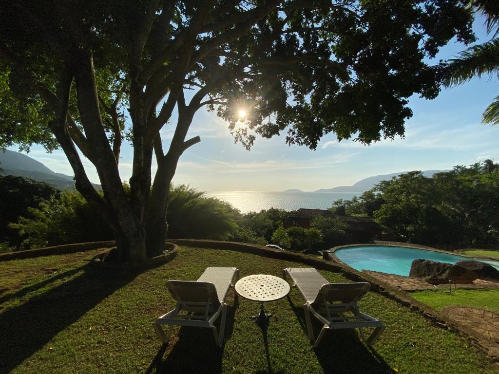 una mesa y dos sillas sentadas junto a una piscina en Villa Galiileu Ilhabela, en Ilhabela