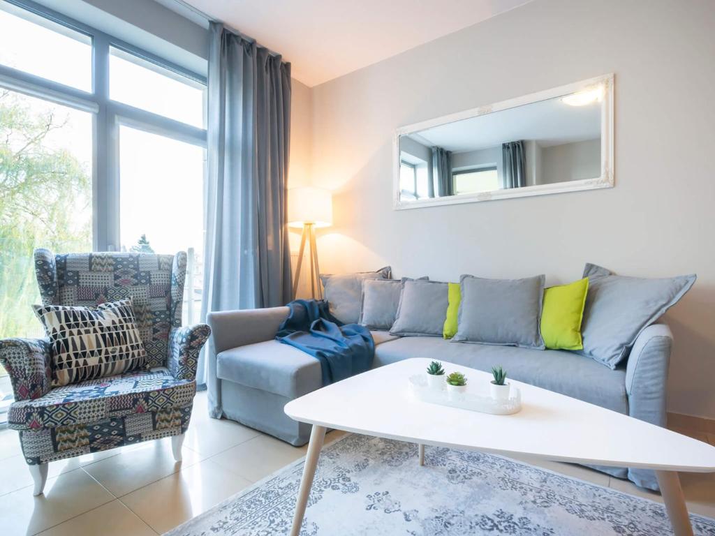 a living room with a couch and a table at VacationClub – Diune Apartment 13 in Kołobrzeg