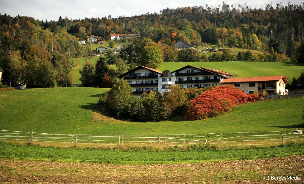 une maison au sommet d'une colline verdoyante plantée d'arbres dans l'établissement Appartement Hauzenberg-Panorama, à Hauzenberg