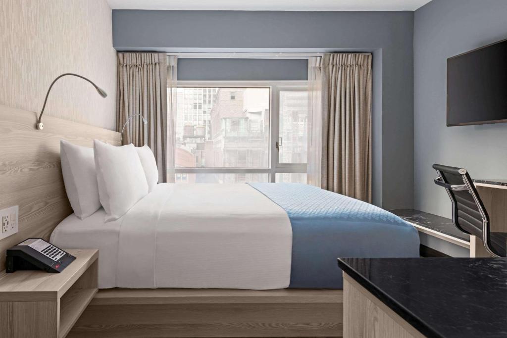 Wingate by Wyndham New York Midtown South/5th Ave في نيويورك: غرفة فندقية بسرير كبير ونافذة