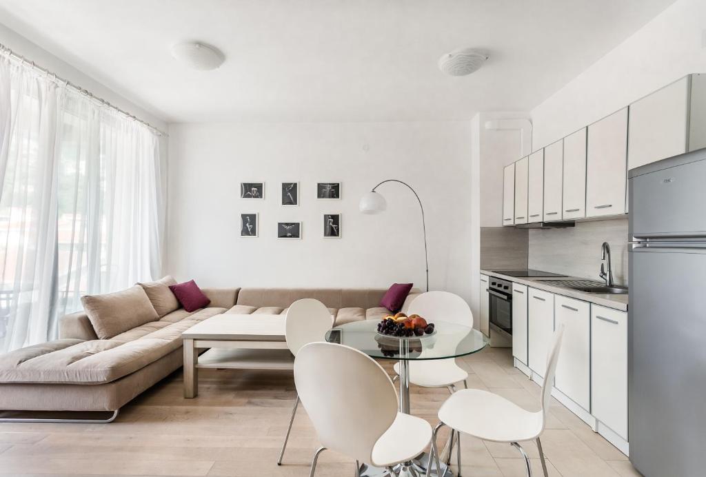a white living room with a couch and a table and chairs at Apartments BEATRICE Rafailovici in Rafailovici