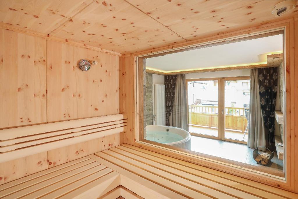 a sauna with a large window and a tub at Verwöhnhotel Kristall in Pertisau