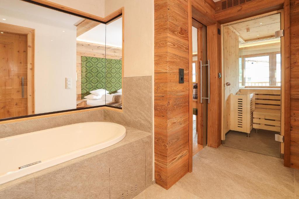 a bathroom with a bath tub and a bedroom at Verwöhnhotel Kristall in Pertisau