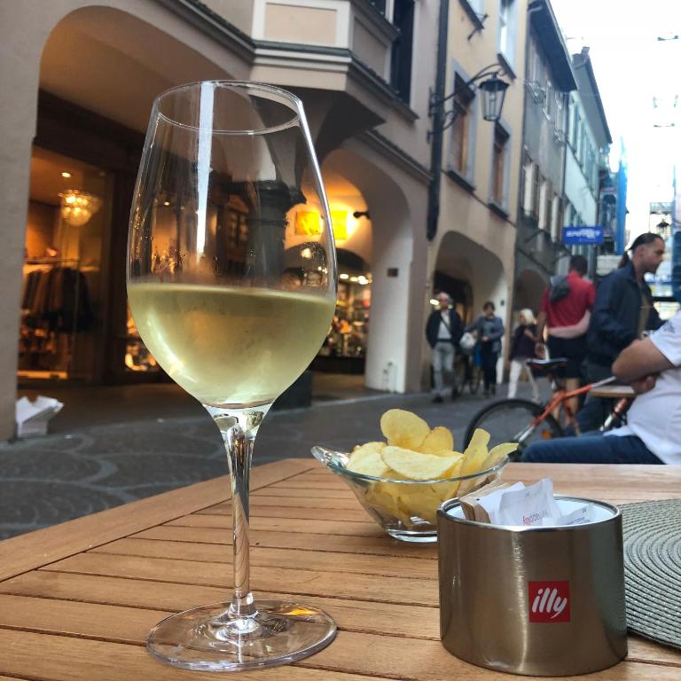 kieliszek białego wina siedzącego na stole w obiekcie City Apartments Portico w Meranie