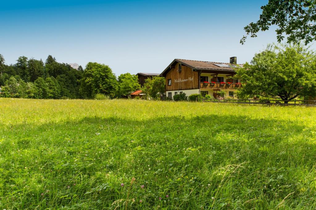 un vaste champ d'herbe avec une maison en arrière-plan dans l'établissement Waldhauser Hof, à Schönau am Königssee