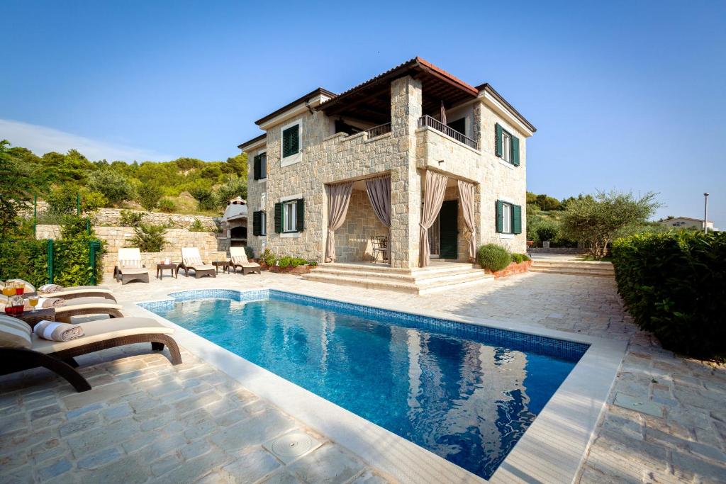 ein Haus mit einem Swimmingpool vor einem Haus in der Unterkunft Villa Diana in Podstrana