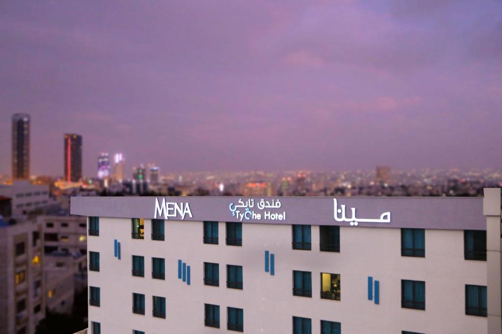 a building with a sign on the top of it at MENA Tyche Hotel Amman in Amman