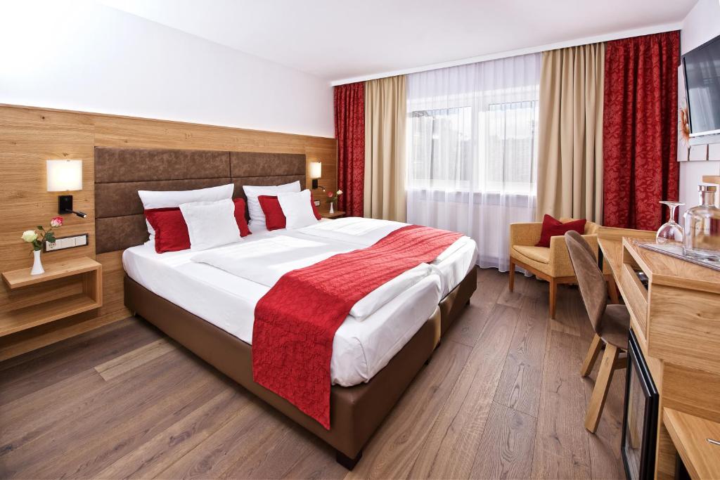 ミュンヘンにあるパーク ホテル ライムの大きなベッドとデスクが備わるホテルルームです。