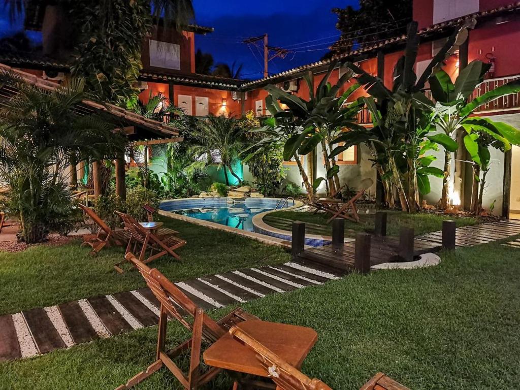 a backyard with a pool and chairs and a building at Pousada Tatuapara in Praia do Forte