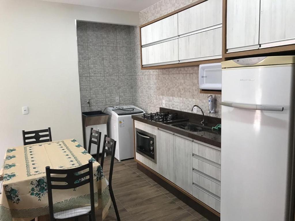 a kitchen with a table and a white refrigerator at Casa - Próximo a UFSC e Centro - 5KM # in Florianópolis