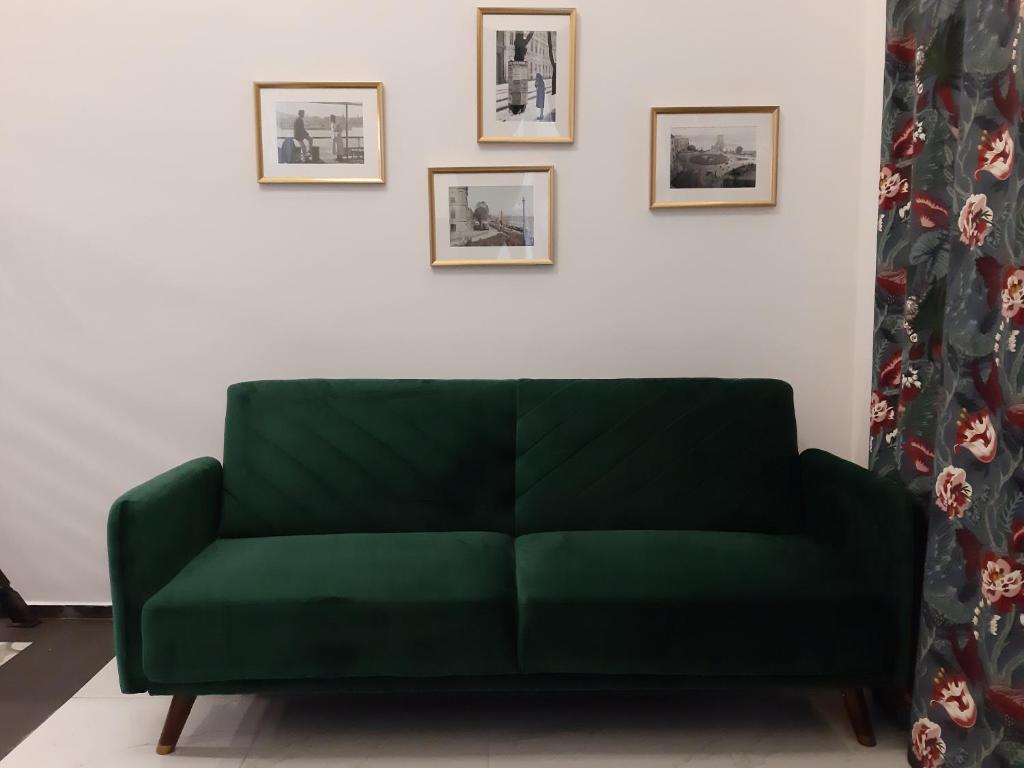 a green couch in a living room with pictures on the wall at Danube Elegance Apartment in Budapest