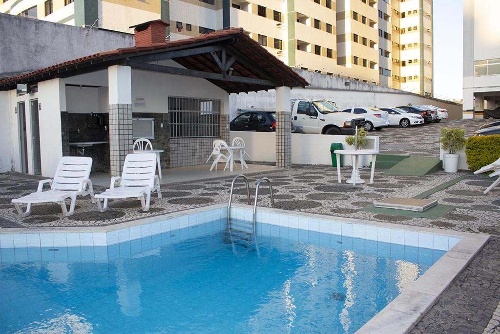 einen Pool mit Stühlen, einem Tisch und einem Gebäude in der Unterkunft Apto Mar Stiep in Salvador