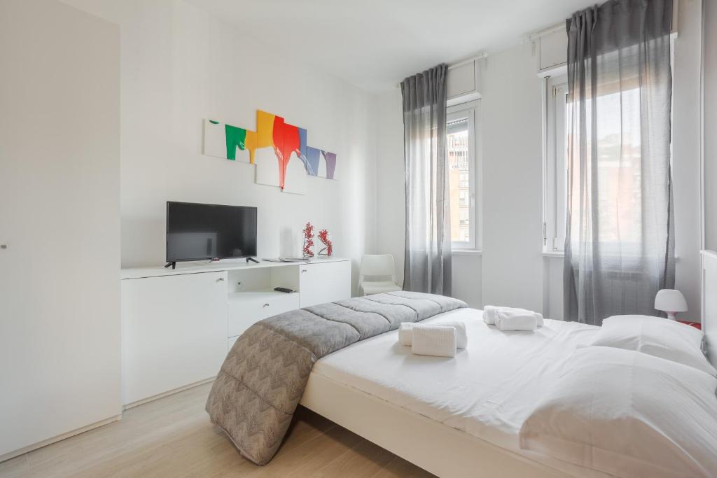 ein weißes Schlafzimmer mit einem Bett und einem TV in der Unterkunft IMHOME - Muratori in Mailand