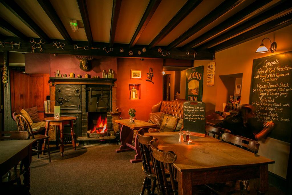 um restaurante com mesas e uma lareira numa sala em Moors Inn em Appleton le Moors