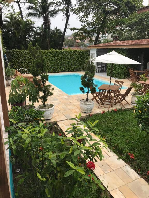 a backyard with a pool and a table and chairs at Santa Cecília Pousada in Guarujá