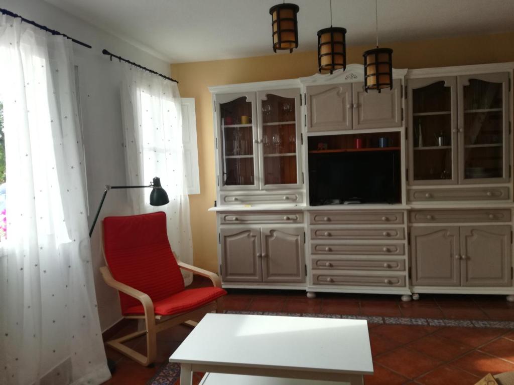 een woonkamer met een tv en een rode stoel bij Casa La Palomera 1 in Valle Gran Rey