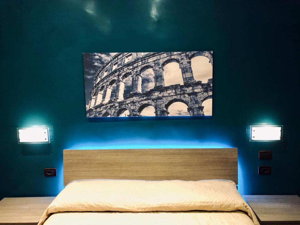 una camera da letto con un dipinto del Colosseo di AR ROOMS ROME a Roma