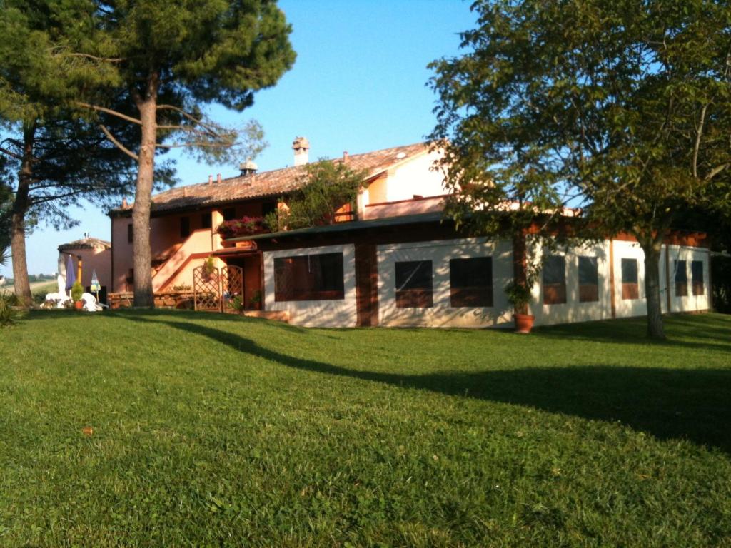 una casa con un césped verde delante de ella en Agriturismo Casale il Gallo Bianco en Offagna