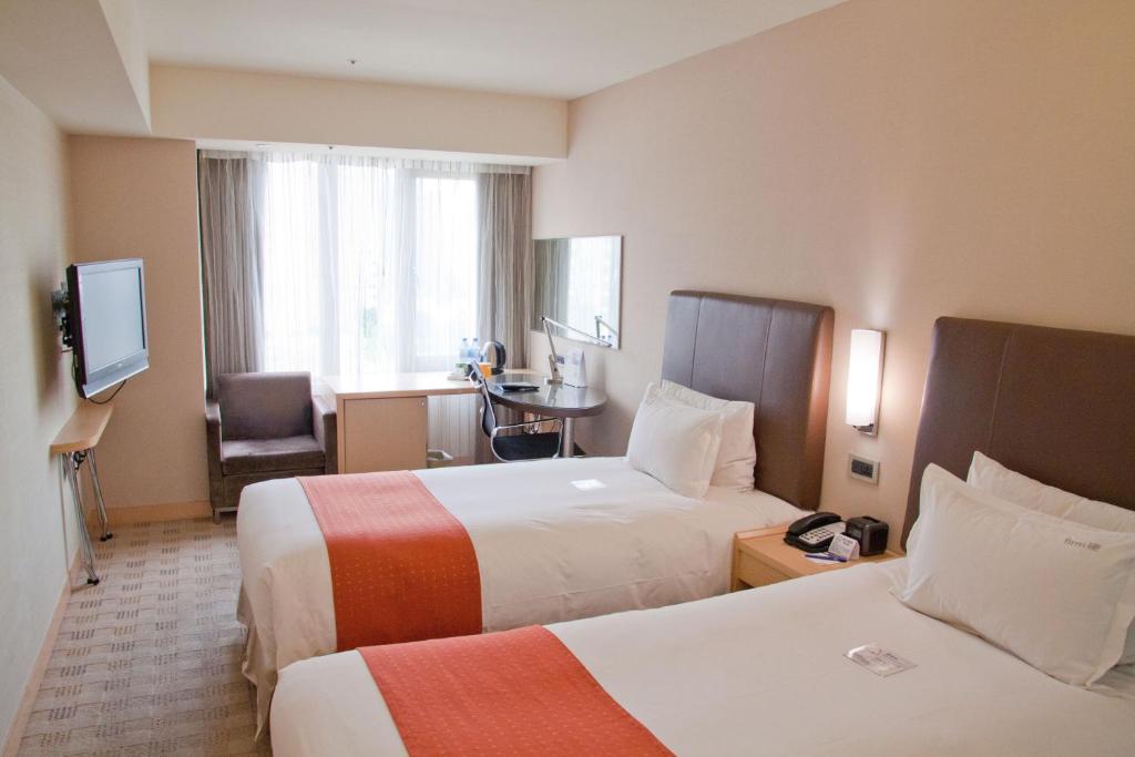 Holiday Inn Express Taoyuan, an IHG Hotel tesisinde bir odada yatak veya yataklar
