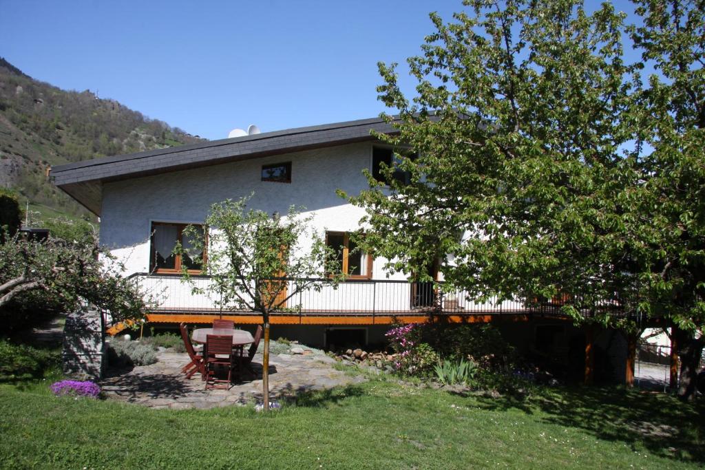 a house with a balcony and a table in a yard at Chalet avec jardin in Bourg-Saint-Maurice