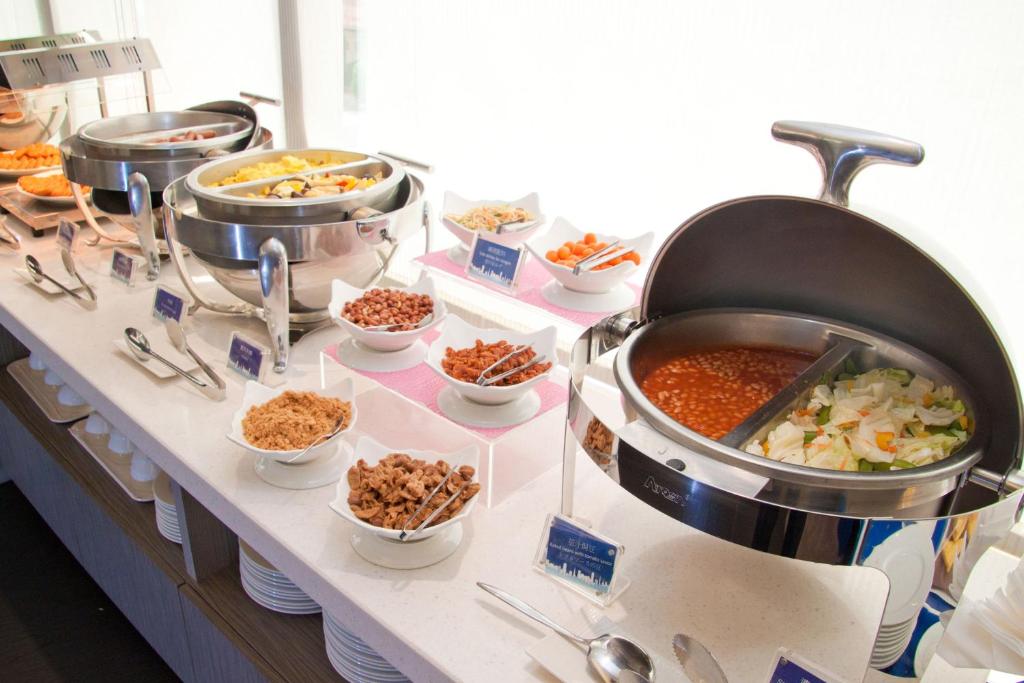 Holiday Inn Express Taoyuan, an IHG Hotel في تاويوان: بوفيه مع العديد من الأطباق المختلفة من الطعام على الطاولة