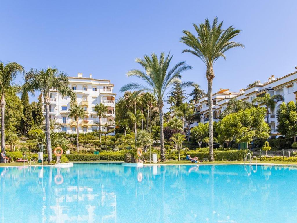 une grande piscine avec des palmiers et des bâtiments dans l'établissement Cozy Apartament in Golden Mile, à Marbella