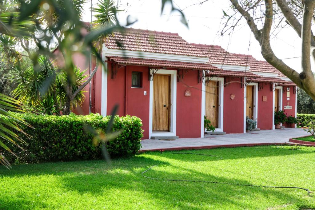 una casa roja con un césped verde delante de ella en Dendrolivano en Minia