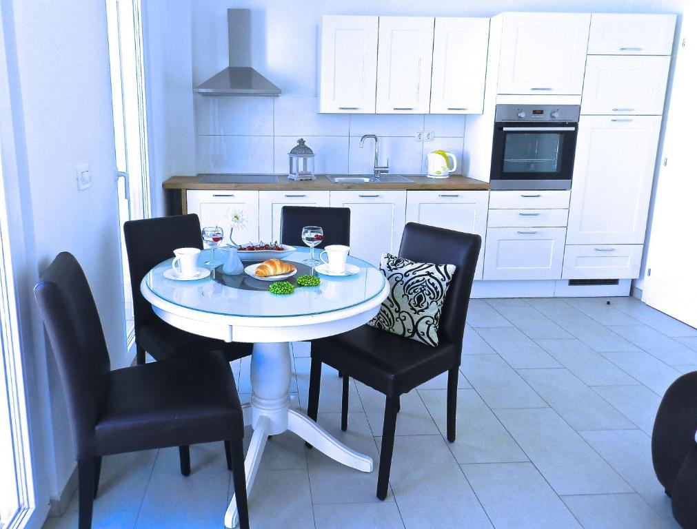 eine Küche mit einem Tisch und Stühlen mit einem Teller Essen drauf in der Unterkunft Diamant Apartments in Baška Voda