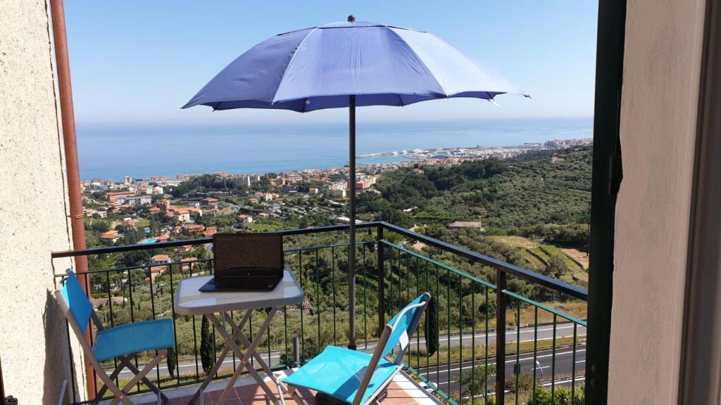 a laptop on a table on a balcony with an umbrella at B&B TRA CIELO e MARE in Pietra Ligure