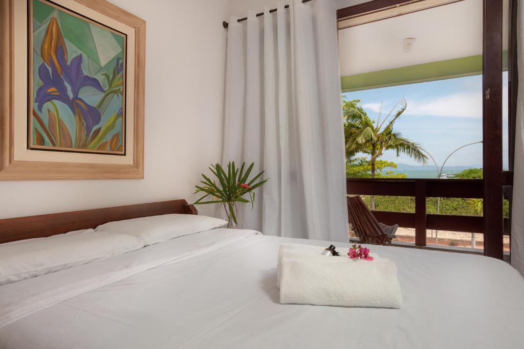 a bedroom with a white bed with a view of the ocean at Vila do Mar in Florianópolis