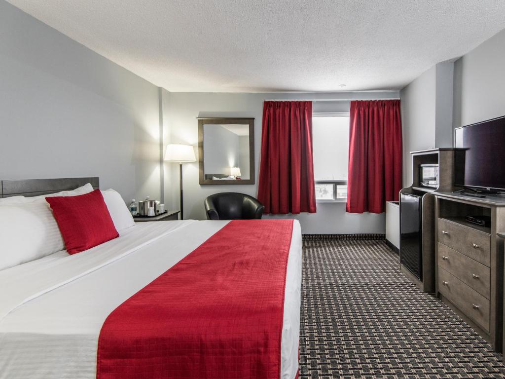 a hotel room with a large bed with a red blanket at Paradise Inn & Conference Centre in Grande Prairie