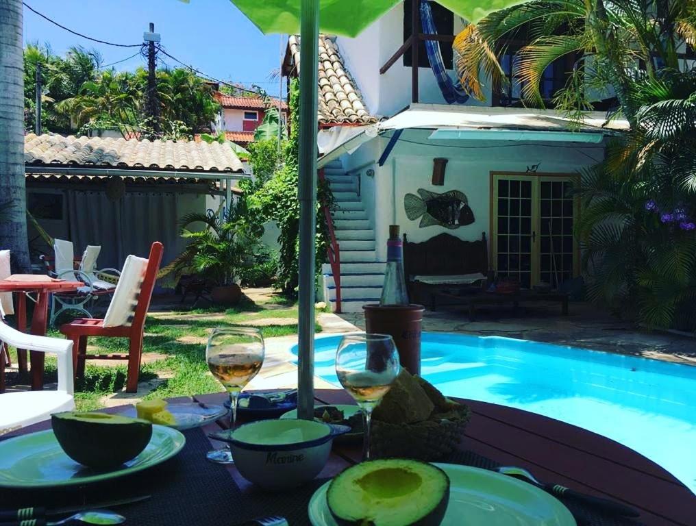 una mesa con copas de vino junto a una piscina en Chez Marine Guest House, en Búzios