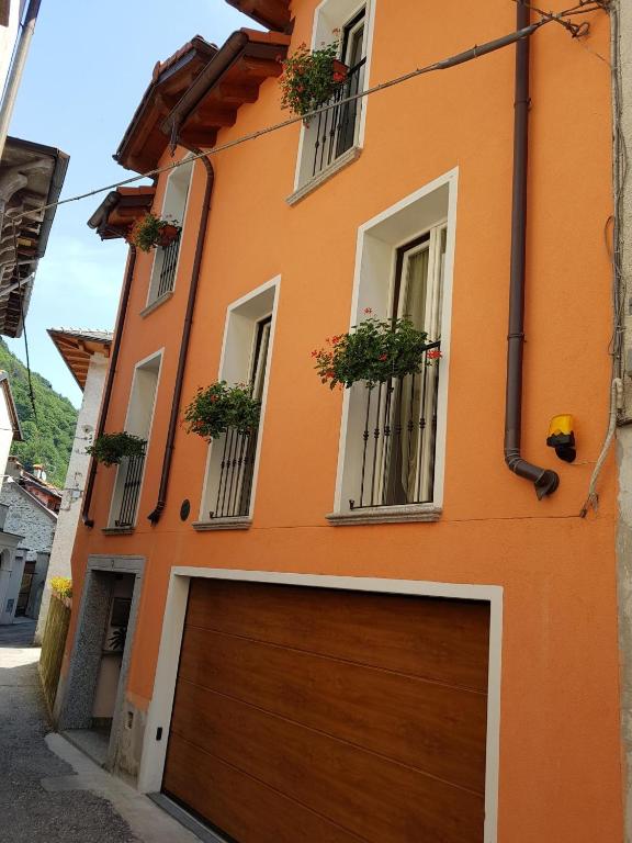 an orange building with a brown garage door and two windows at Casa Cuor Di Leone in Cannobio