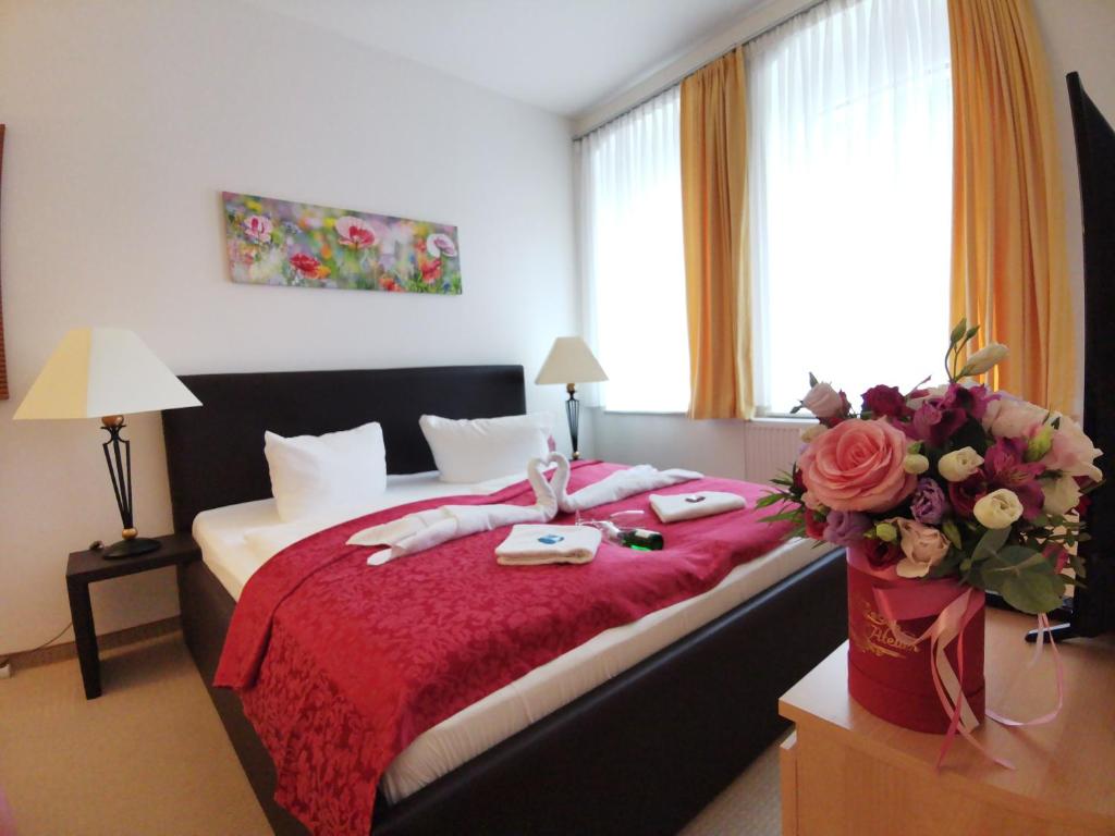 sypialnia z łóżkiem z czerwonym kocem i kwiatami w obiekcie Apartments Fichtelberger Blick w mieście Kurort Oberwiesenthal
