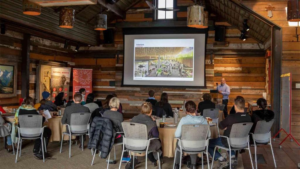 un gruppo di persone seduti ai tavoli in una stanza con presentazione di The Headwaters Eco Lodge a Glenorchy