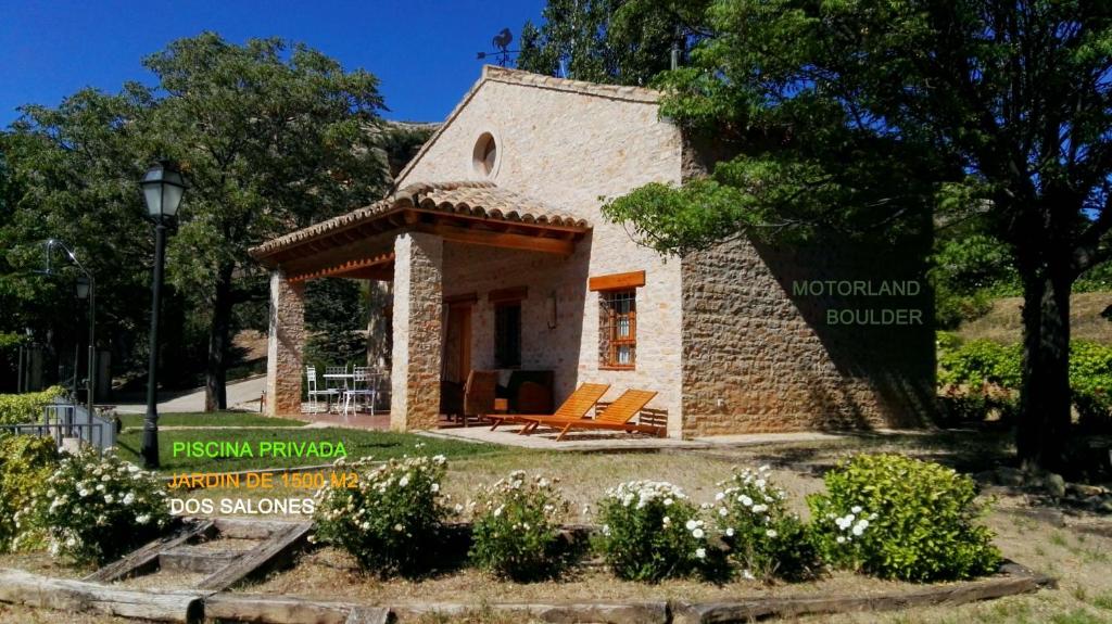 a small stone house in a garden with flowers at La Casa de Concha (Alojamiento entero) in Alcañiz