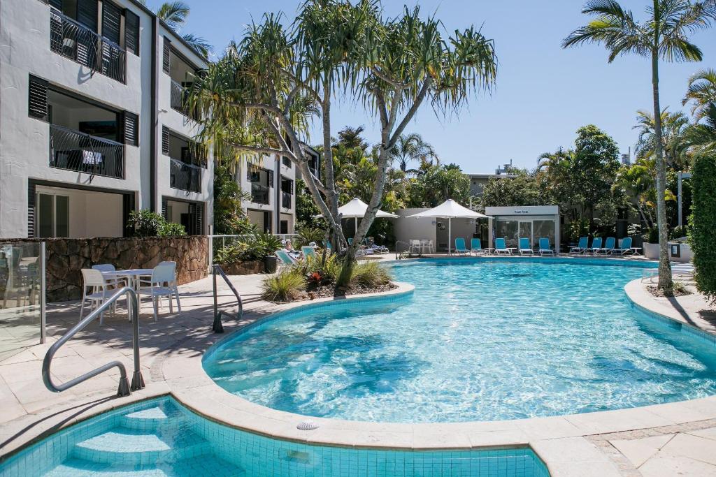 a swimming pool at a resort with palm trees at Noosa Blue Resort in Noosa Heads