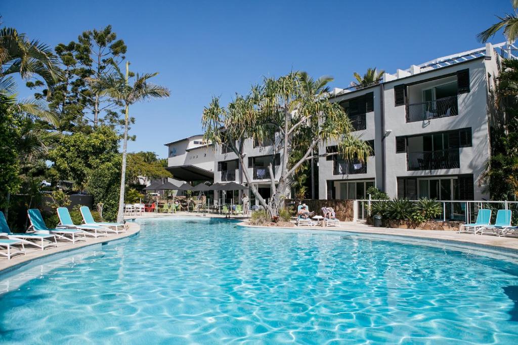 a swimming pool with chairs and a building at Noosa Blue Resort in Noosa Heads