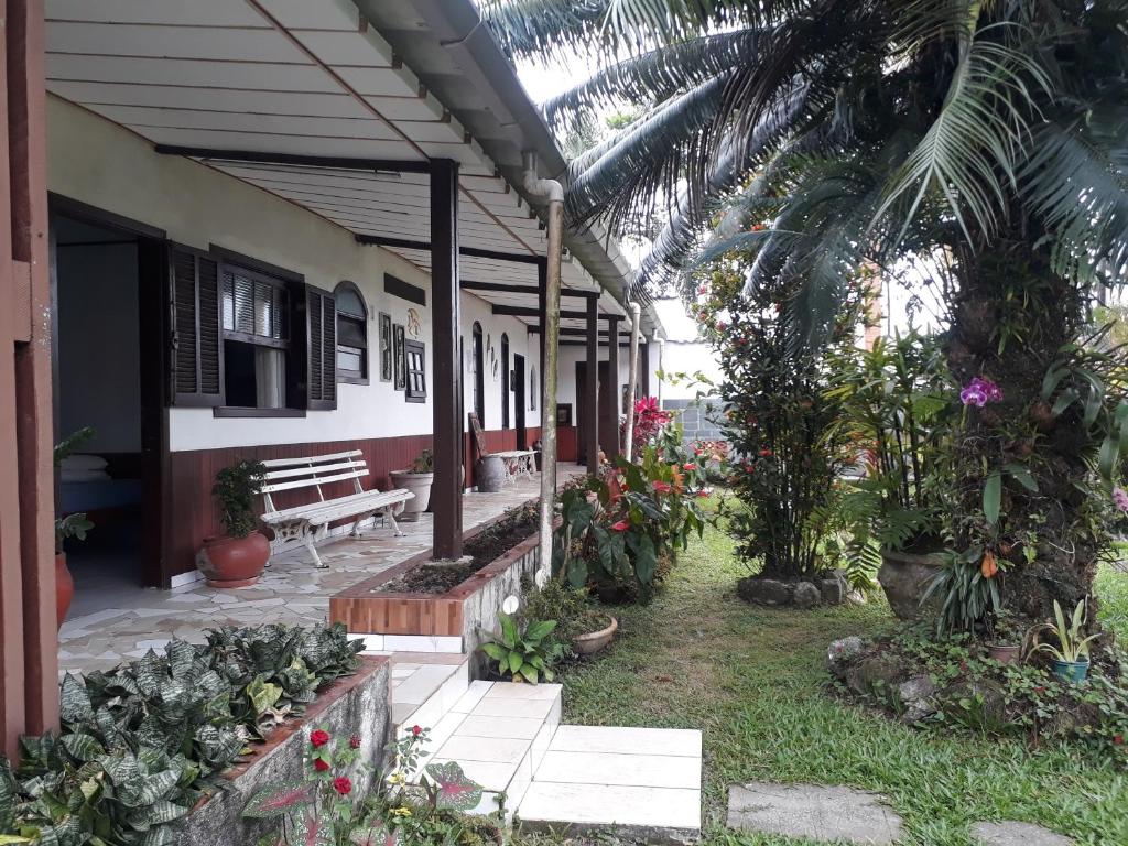 une terrasse couverte d'une maison avec un banc et des fleurs dans l'établissement Pousada da Geisa, à Bertioga