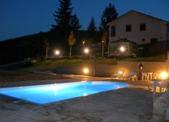 a swimming pool in front of a house at night at Cà Du Ruja in Strevi